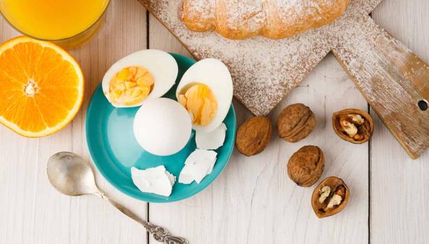 Huevos cocidos, acompañados por jugo de naranja y un croissant.