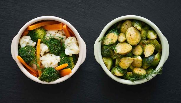 Zanahoria, brócoli y otras verduras que se suelen cocinar al vapor, servidas en dos tazas.