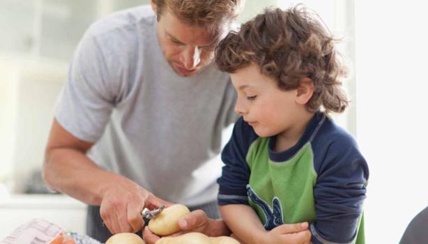 Padre e hijo pelando alimentos en la cocina