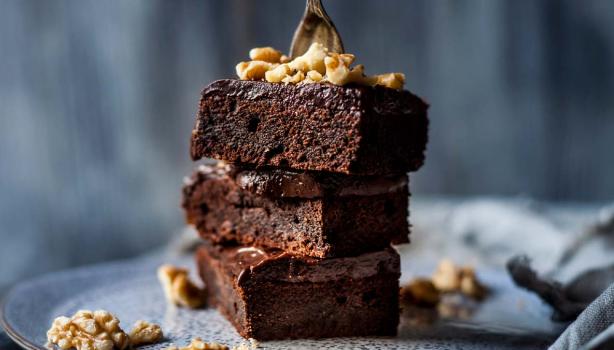 Plato con tres pisos de brownie espolvoreado con nueces, este es un postre sin gluten 