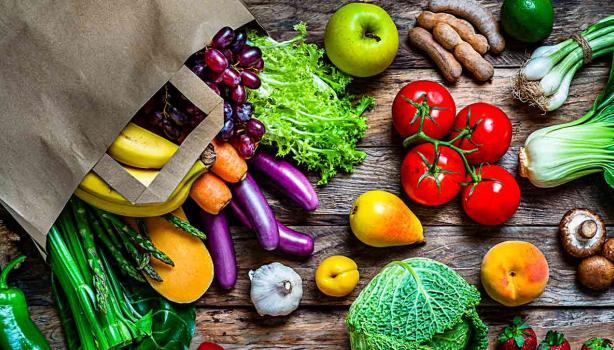 Múltiples frutas y verduras regadas sobre una mesa, que son alimentos que aportan vitaminas esenciales
