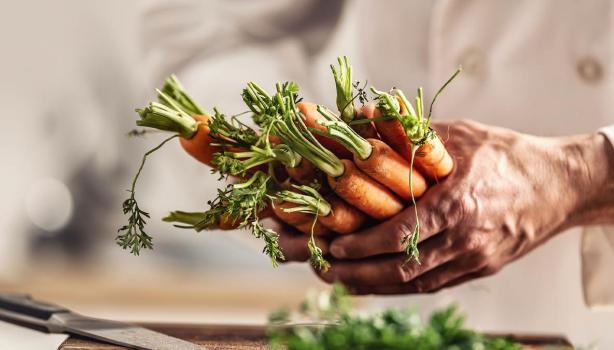 Persona cocinando con zanahorias y creando su plantilla de menú semanal