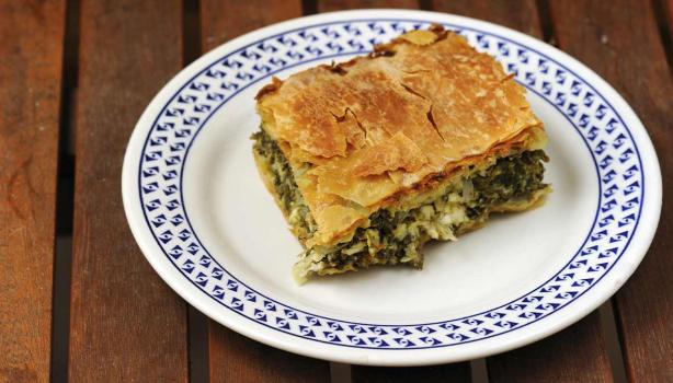 Una porción de la receta griega spanakopita sobre un plato blanco y azul