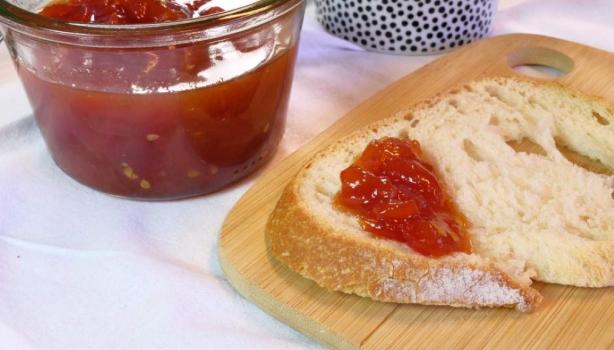Rebanada de pan con mermelada casera de fresa, recipiente de vidrio sobre tabla