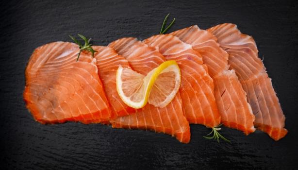 Pequeños trozos de salmón ahumado frío sobre fondo negro.