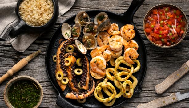 Sartén de hierro fundido con pulpo a la parrilla y variedad de mariscos