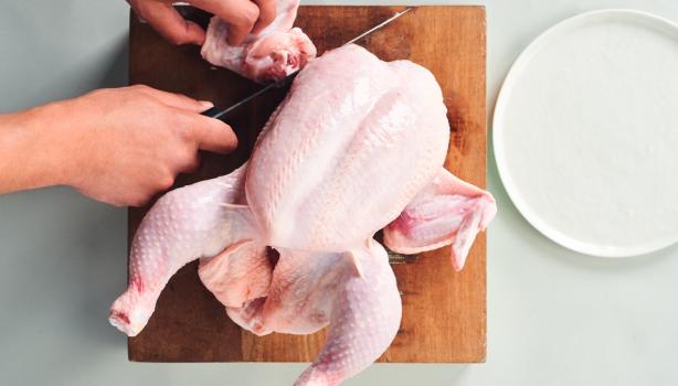 Corte de la carcasa de pollo sobre una tabla de madera, ideal para usar en caldos de hueso de pollo