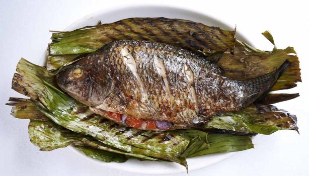 Pescado a la parrilla sobre hojas de plátano.
