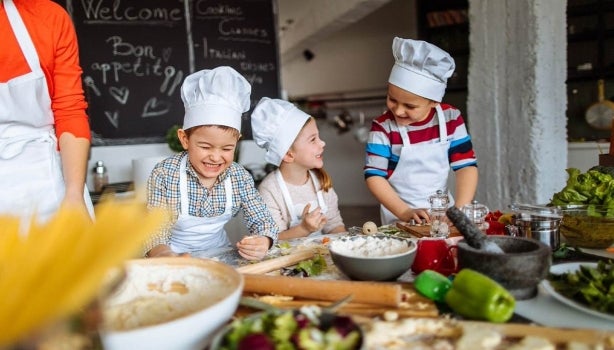 Tres niños preparando recetas alegremente.