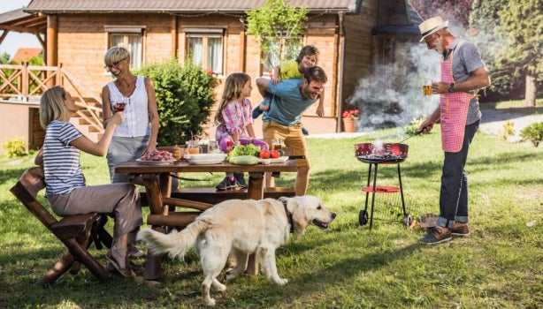 Familia reunida cocinando carne a la parrilla al aire libre.