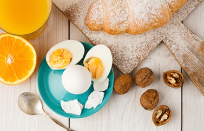 Huevos cocidos, acompañados por jugo de naranja y un croissant.