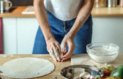 Mujer con utensilios e ingredientes preparando masa para pizza Mujer con utensilios e ingredientes preparando masa para pizza