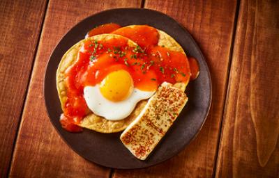 Un desayuno con huevo, tortillas y salsa.