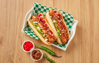 Plato con hot dogs, cebollas caramelizadas, tomates y chiles