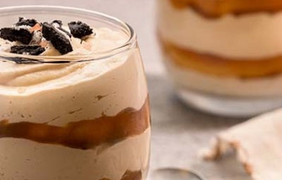 Un postre en vaso con dulce de leche y galletas. 