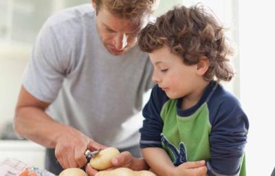 Padre e hijo pelando alimentos en la cocina Padre e hijo pelando alimentos en la cocina