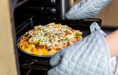 Sacar receta del horno utilizando guantes y agarraderas de cocina 