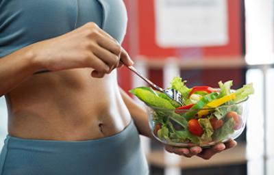 Una mujer con una ensalada después de salir a hacer ejercicio en una rutina de vida activa Una mujer con una ensalada después de salir a hacer ejercicio en una rutina de vida activa
