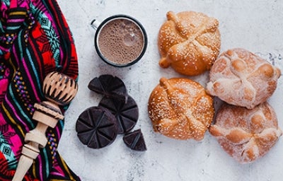 Panes dulces mexicanos tradicionales acompañados de chocolate caliente y un molinillo