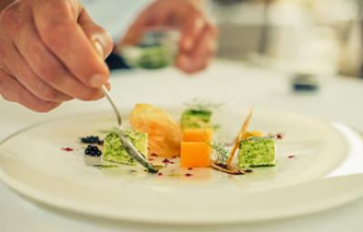 Una persona emplatando con una cuchara una comida con caviar Una persona emplatando con una cuchara una comida con caviar