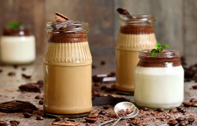 Tres tipos de mousse en vaso con una cuchara y chocolate espolvoreado