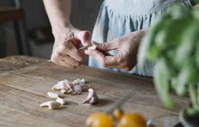 Mujer pelando ajos con cuchillo, qué hacer al cortarse en la cocina Mujer pelando ajos con cuchillo, qué hacer al cortarse en la cocina