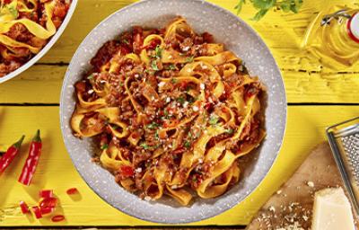 Pasta a la boloñesa con carne, queso parmesano y hierbas aromáticas sobre un fondo amarillo. Pasta a la boloñesa con carne, queso parmesano y hierbas aromáticas sobre un fondo amarillo.