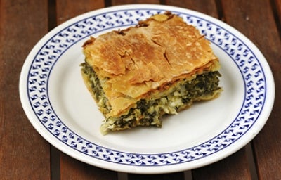 Una porción de la receta griega spanakopita sobre un plato blanco y azul Una porción de la receta griega spanakopita sobre un plato blanco y azul