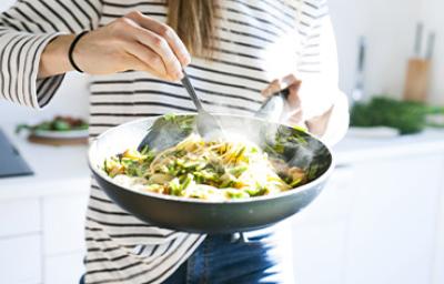 Una persona cocinando su comida con menos de 5 ingredientes en una sartén