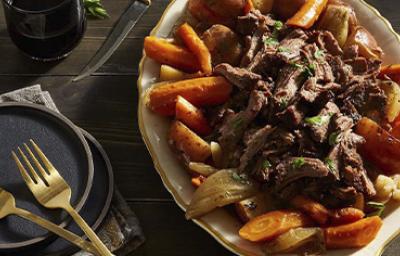 Pedazos de carne de cabrito asado con especias sobre una cama de vegetales y papas Pedazos de carne de cabrito asado con especias sobre una cama de vegetales y papas