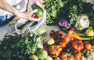Una persona sacando productos orgánicos, frutas y verduras de una bolsa Una persona sacando productos orgánicos, frutas y verduras de una bolsa