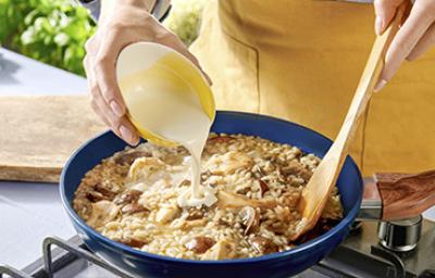 Una persona preparando una receta de cocción lenta con champiñones, crema y arroz. Una persona preparando una receta de cocción lenta con champiñones, crema y arroz.