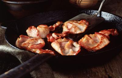 Pedazos de panceta fritos Deliciosa panceta cortada siendo fritada en un sartén