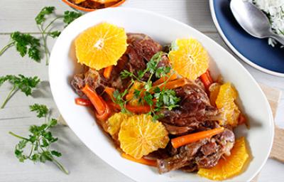 Plato de cerdo con salsa de naranja, acompañado de rodajas de naranja