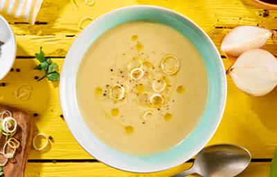 Vichyssoise en un tazón, mesa amarilla con ingredientes frescos