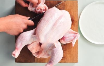 Cómo cortar la carcasa de pollo para preparar caldos y sopas Corte de la carcasa de pollo sobre una tabla de madera, ideal para usar en caldos de hueso de pollo