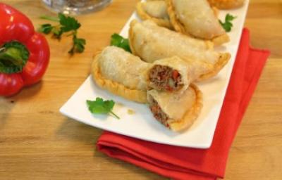 Empanadillas de arroz, un snack rico y nutritivo. Platillo lleno de empandillas de arroz sobre servilleta roja y junto a un pimiento.