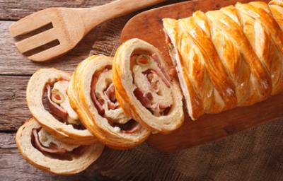 Pancitos de jamón, preparación propia de la panadería latina. Pancitos de jamón tajado en cuatro pesados sobre tabla de picar.