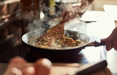 Cocina para principiantes, fácil y sencillo. Persona cocinando huevos en un sartén con la guía de cocina para principiantes.