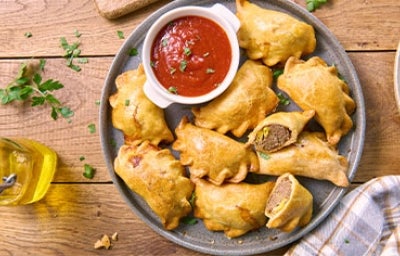 Empanada, entrada de comida ideal para fiestas colombianas. Bandeja de empanadas con ají como entrada de comida para fiesta.