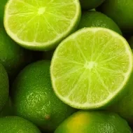 Un limón, uno de los cítricos más usados, partido por la mitad, encima de más limones. 