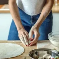 Mujer con utensilios e ingredientes preparando masa para pizza