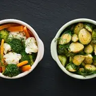 Zanahoria, brócoli y otras verduras que se suelen cocinar al vapor, servidas en dos tazas.