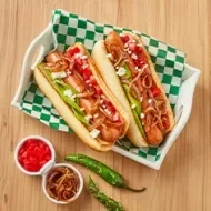 Plato con hot dogs, cebollas caramelizadas, tomates y chiles