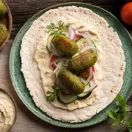 El falafel es una comida libanesa que se consume en todo Medio Oriente Falafel con verduras, tahini y pan pita, una comida libanesa tradicional.