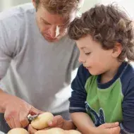 Padre e hijo pelando alimentos en la cocina