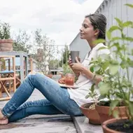 Una mujer con un vaso y un plato de comida aprovechando un buen descanso