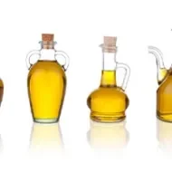 Cuatro jarras con aceite de ajonjolí en un fondo blanco