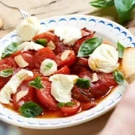 Ensalada caprese con tomate, queso, albahaca y pan en un plato