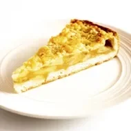 Una porción de tarta de lychees y almendras en un plato blanco